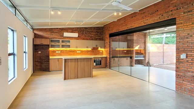 Open-plan kitchen with island and exposed brick